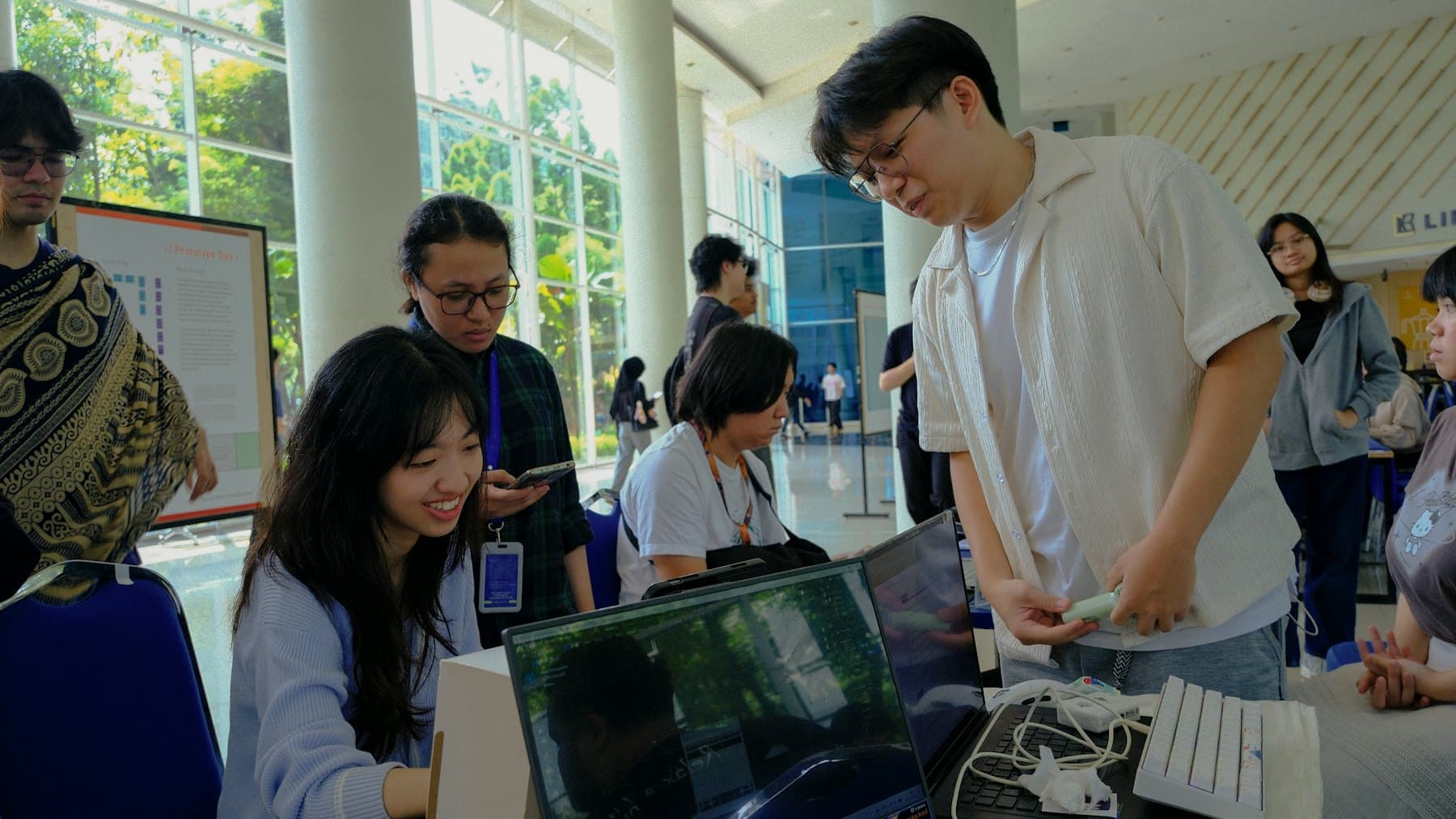 Students showing a project on their laptops to visitors at a university showcase